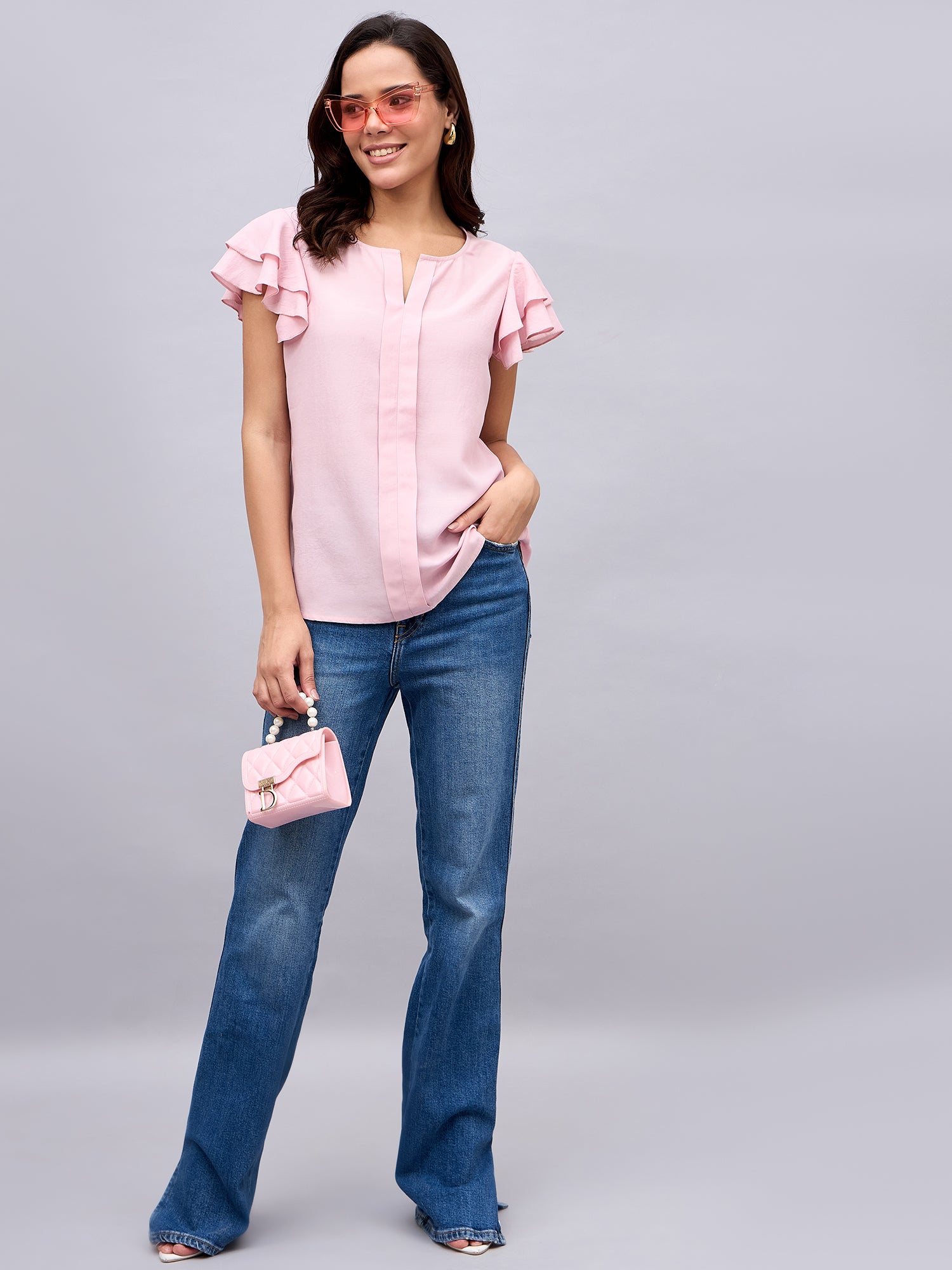 Model styled in NUWAH pink ruffle top with handbag – full look
