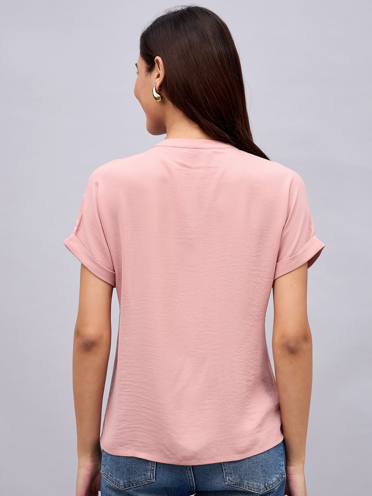 Back view of soft pink NUWAH top showing cuffed sleeves and relaxed fit
